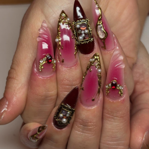 ongles pointus roses avec des strass rouges, des perles et des décorations dorées